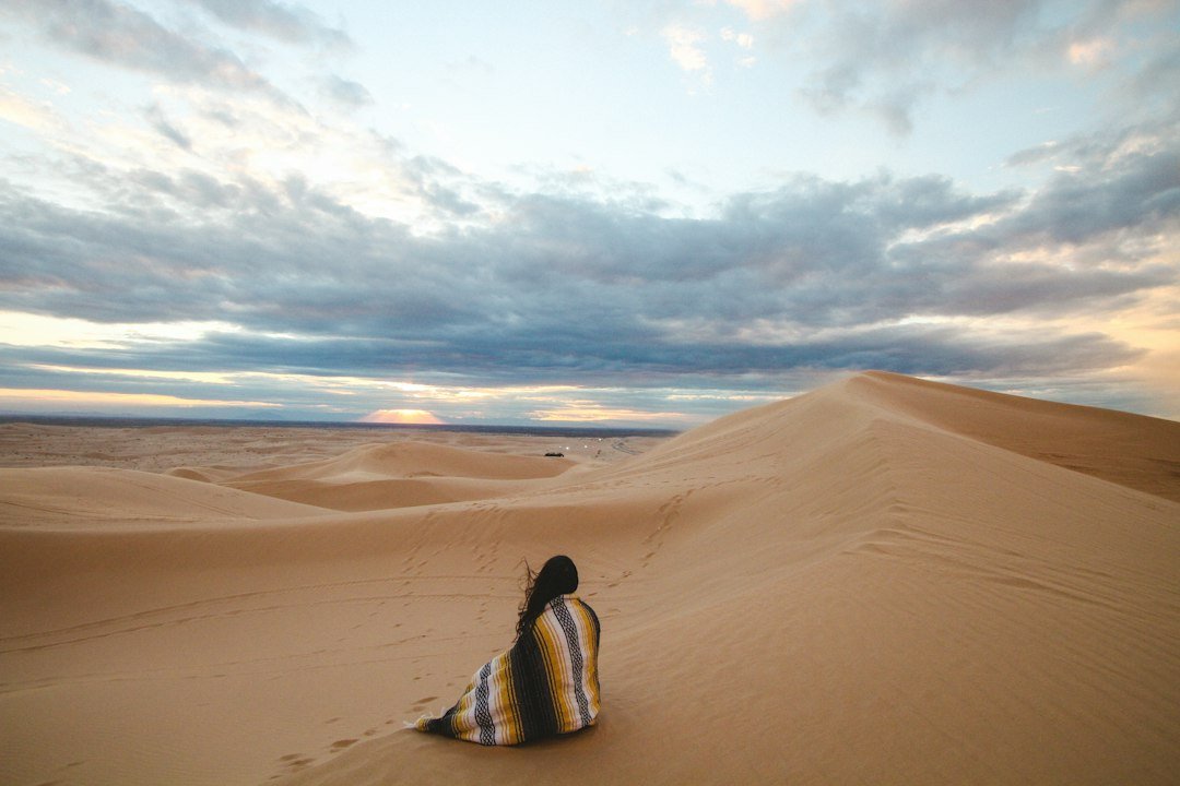Person walking across desert sand dunes